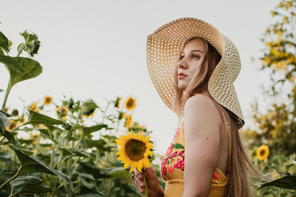 Modno oblečena mlada ženska sredi polja sončnic